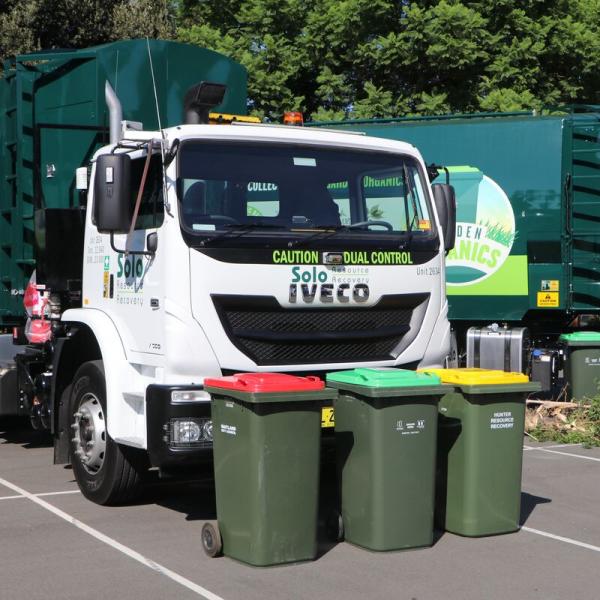 Garbage truck with each colour bin in on ground in front