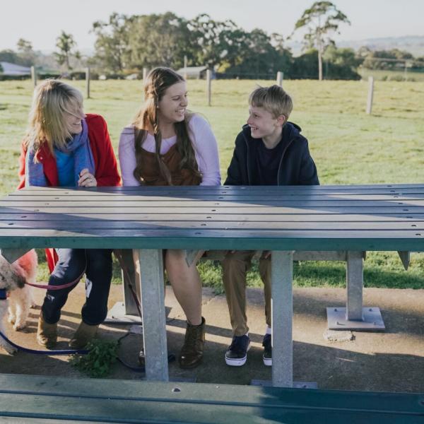 Three children sitting at a table in park at Bolwarra