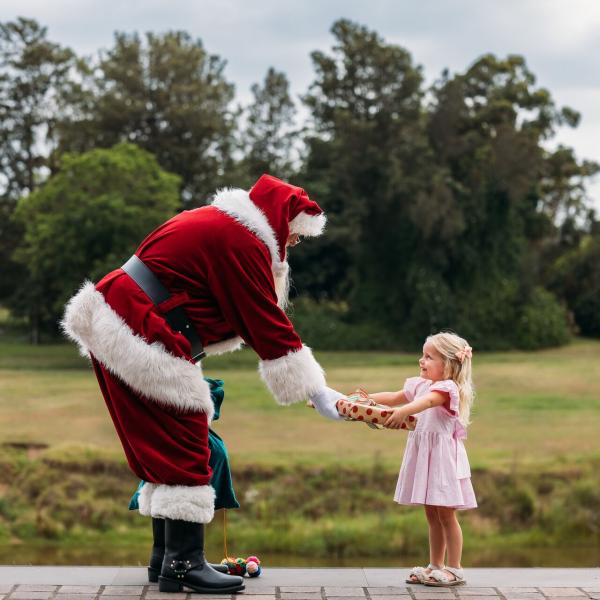 Santa at The Levee handing a gift to a child