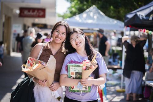 Two ladies holding flowers at markets
