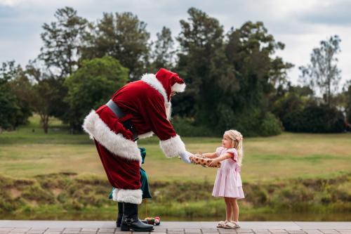 Santa at The Levee handing a gift to a child