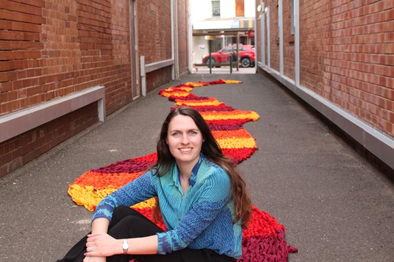 Michaela Swan sitting in front of art installation