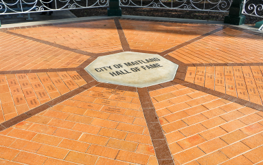 Cement plaque says City of Maitland Hall of Fame, surrounded by bricks bearing names of inductees.