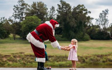 Santa at The Levee handing a gift to a child