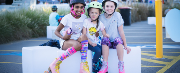 Three girls sitting with roller skates on