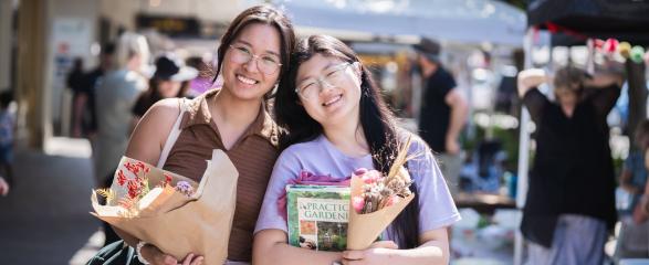 Two ladies holding flowers at markets