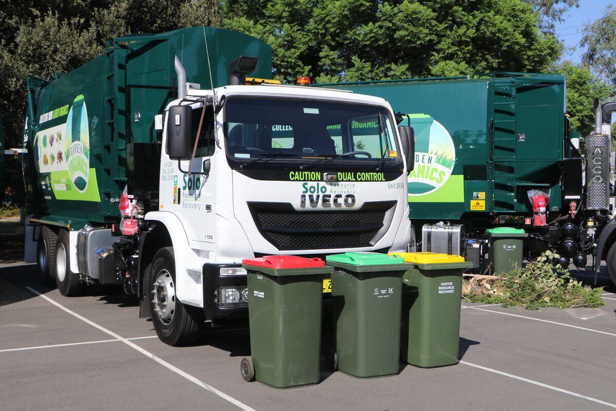 Garbage truck with each colour bin in on ground in front