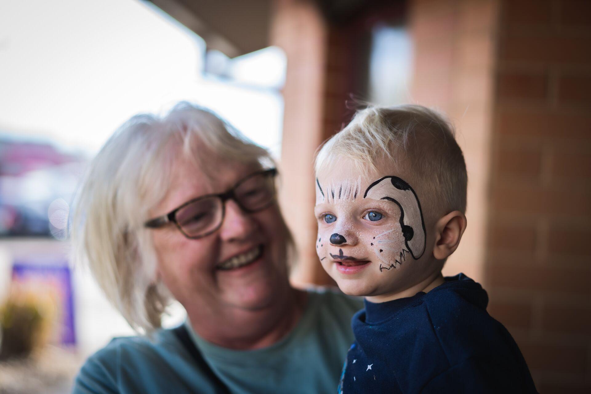 Women holding child with face painted