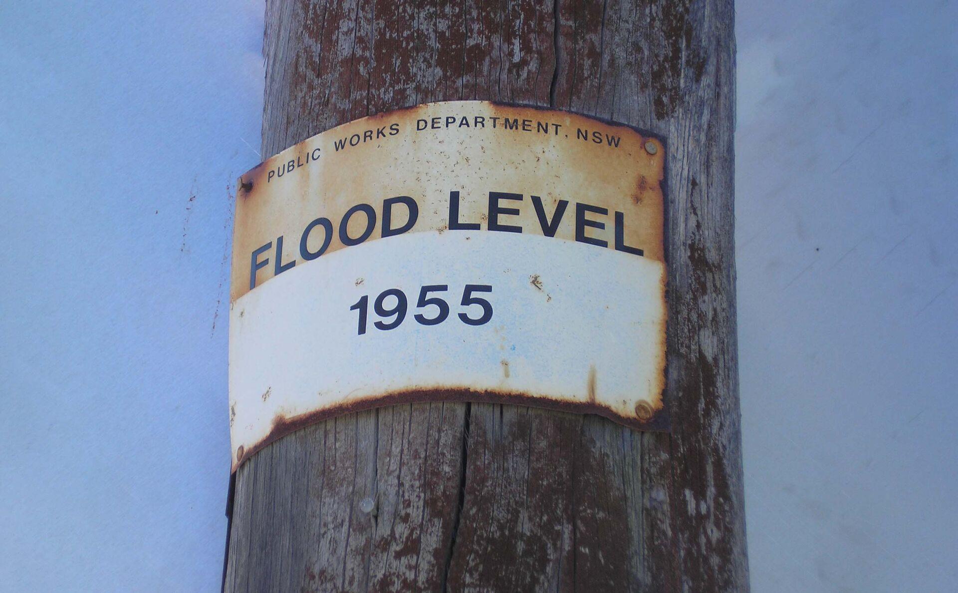 A sign on a post indicating the flood level of 1955